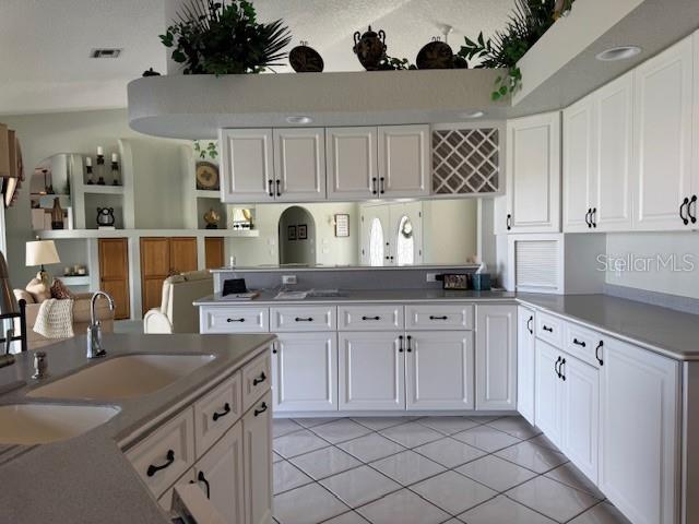 507 Monaco Dr, Punta Gorda, FL 33950 - kitchen featuring a peninsula, light tile patterned flooring, white cabinetry, a sink, and open floor plan