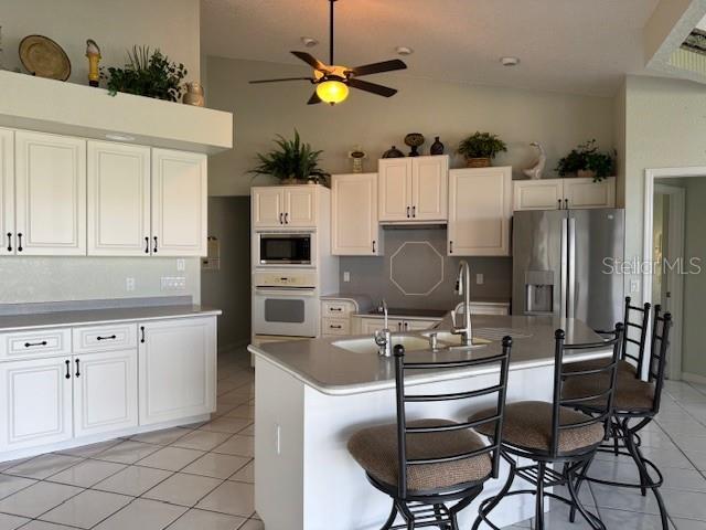 507 Monaco Dr, Punta Gorda, FL 33950 - kitchen with appliances with stainless steel finishes, a ceiling fan, light tile patterned floors, lofted ceiling, and white cabinets