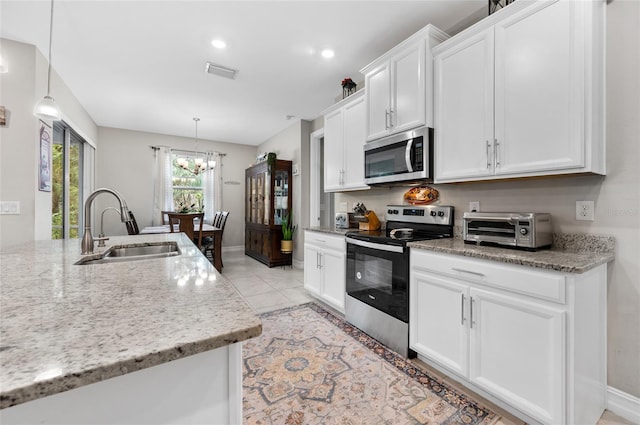 kitchen with a sink, visible vents, white cabinets, appliances with stainless steel finishes, and pendant lighting