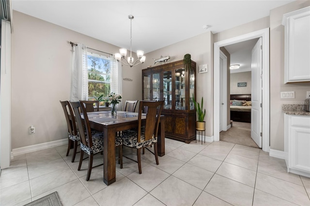 dining space featuring light tile patterned floors, baseboards, and a notable chandelier