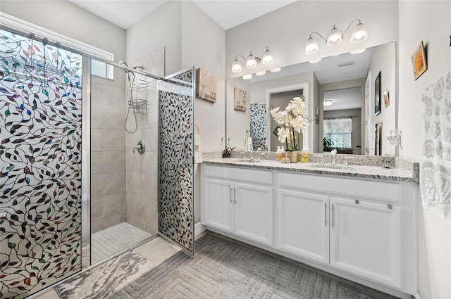 bathroom featuring double vanity, a wealth of natural light, a tile shower, and a sink