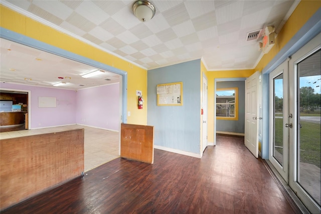 unfurnished room featuring french doors, visible vents, ornamental molding, wood finished floors, and baseboards