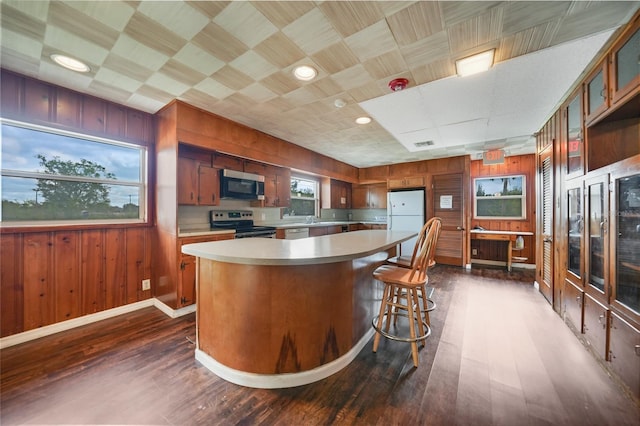 kitchen with stainless steel appliances, dark wood-style flooring, light countertops, and wooden walls