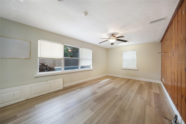 empty room featuring light wood finished floors, a ceiling fan, visible vents, and baseboards