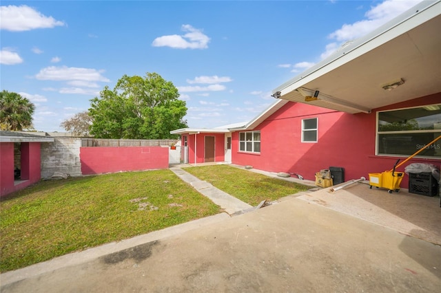 view of front of house with a patio area, fence, a front lawn, and stucco siding