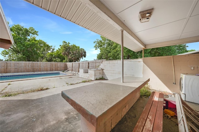 view of patio with a fenced backyard, separate washer and dryer, and a fenced in pool