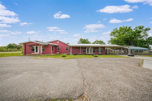 ranch-style house featuring a carport, gravel driveway, and a front lawn