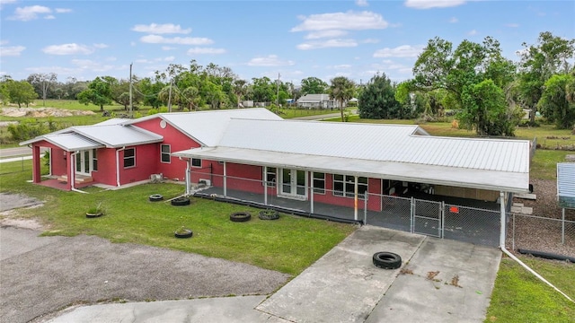 view of front facade with concrete driveway, fence, metal roof, a carport, and a front lawn