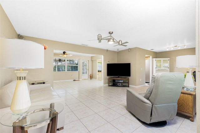 living area with light tile patterned floors, baseboards, and a ceiling fan