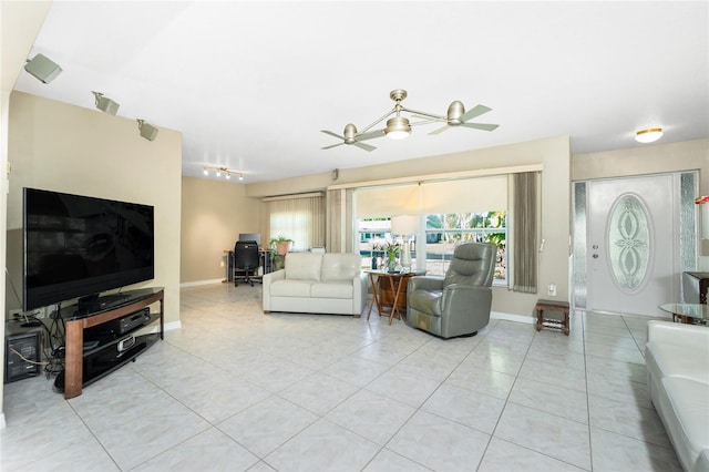 living area featuring light tile patterned floors, a ceiling fan, and baseboards