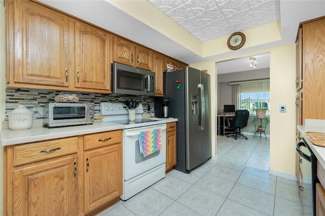 kitchen featuring appliances with stainless steel finishes, light countertops, light tile patterned floors, decorative backsplash, and baseboards