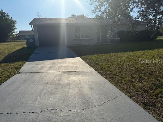 ranch-style home with driveway, an attached garage, and a front lawn