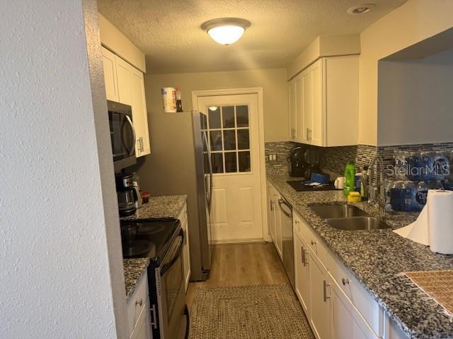 kitchen featuring appliances with stainless steel finishes, stone counters, decorative backsplash, and white cabinets