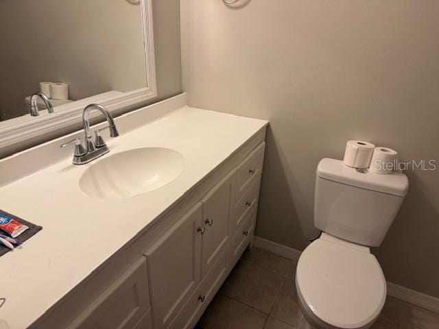 bathroom with tile patterned flooring, baseboards, vanity, and toilet