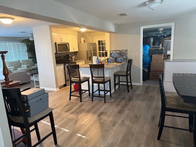 kitchen featuring stainless steel appliances, a peninsula, visible vents, a kitchen breakfast bar, and light wood-type flooring