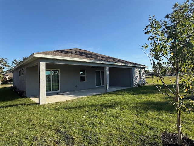 back of house with a patio, roof with shingles, stucco siding, ceiling fan, and a lawn