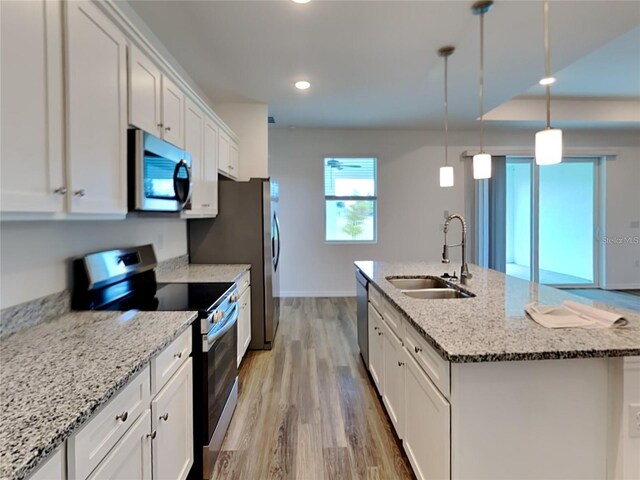 kitchen featuring a center island with sink, light wood-style flooring, white cabinets, stainless steel appliances, and a sink