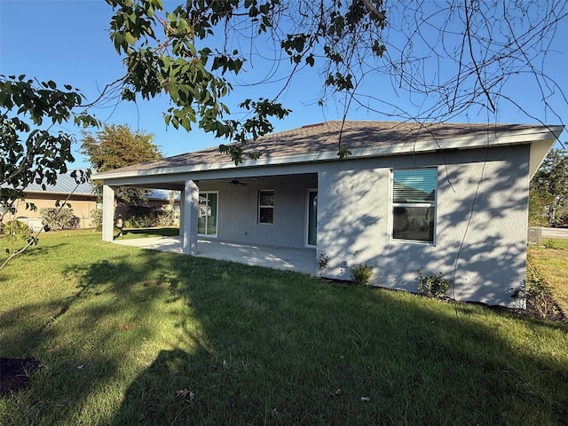 rear view of house with a yard, a ceiling fan, and a patio area