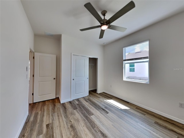 unfurnished bedroom with a closet, a ceiling fan, baseboards, and wood finished floors