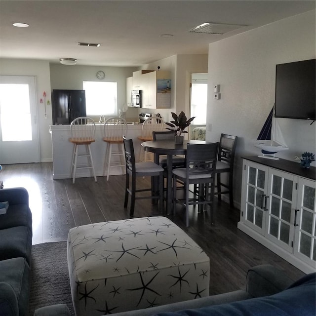 living area with a healthy amount of sunlight, visible vents, and wood finished floors