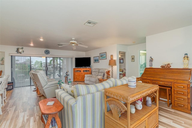 living room with light wood-style floors, visible vents, and a ceiling fan