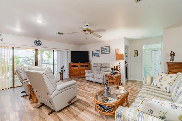 living room with a ceiling fan, light wood-type flooring, visible vents, and baseboards