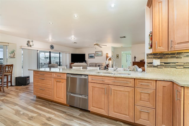 kitchen featuring a peninsula, a sink, open floor plan, stainless steel dishwasher, and decorative backsplash