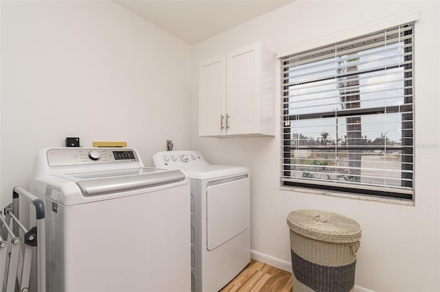 clothes washing area with light wood-type flooring, cabinet space, baseboards, and independent washer and dryer