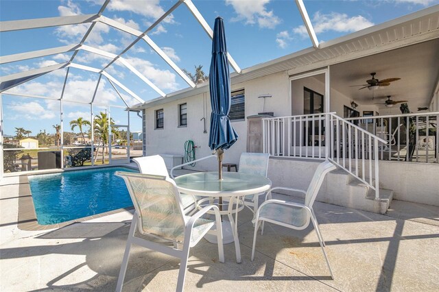 pool with a patio, glass enclosure, outdoor dining area, and a ceiling fan