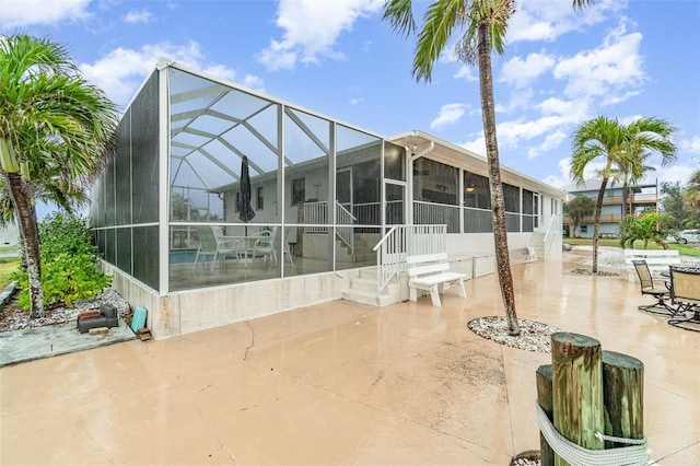 rear view of house with glass enclosure and a patio area