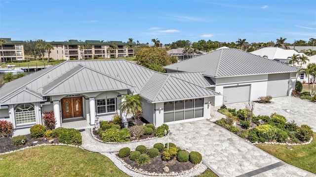 view of front of house featuring stucco siding, an attached garage, a standing seam roof, metal roof, and driveway