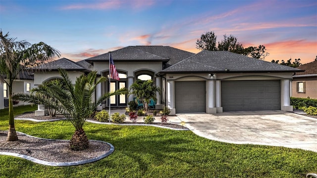 view of front facade with a garage, driveway, a front lawn, and stucco siding