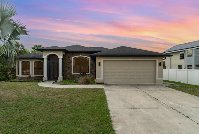 view of front of property with a front yard, concrete driveway, fence, and stucco siding