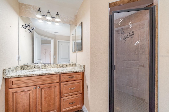 bathroom featuring a stall shower, a textured wall, and vanity