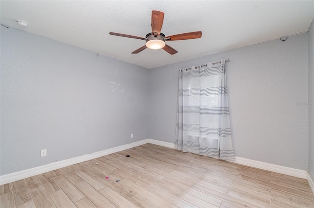 spare room featuring light wood-style floors, baseboards, and a ceiling fan