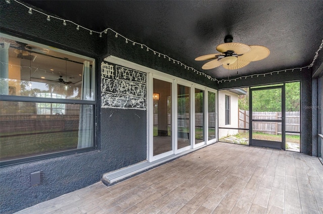 unfurnished sunroom featuring ceiling fan and track lighting