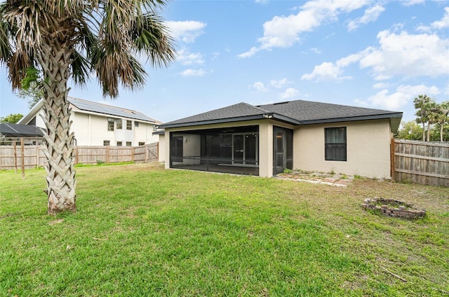 back of house featuring a yard, stucco siding, a shingled roof, a sunroom, and a fenced backyard