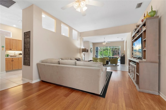 living area featuring baseboards, visible vents, and light wood finished floors