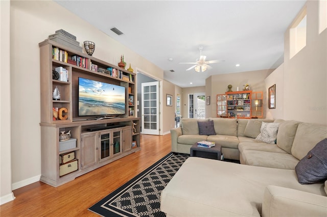 living area featuring a ceiling fan, baseboards, visible vents, and light wood finished floors