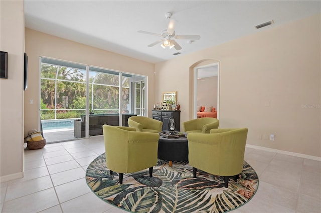 living area with light tile patterned floors, a ceiling fan, visible vents, and baseboards