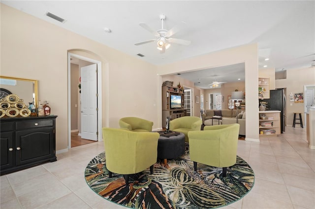 living area with ceiling fan, visible vents, arched walkways, and light tile patterned flooring