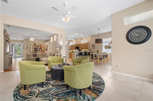 living area with light tile patterned floors, ceiling fan, and a healthy amount of sunlight