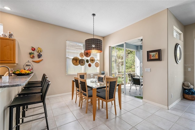 dining room with light tile patterned floors, baseboards, and a textured ceiling