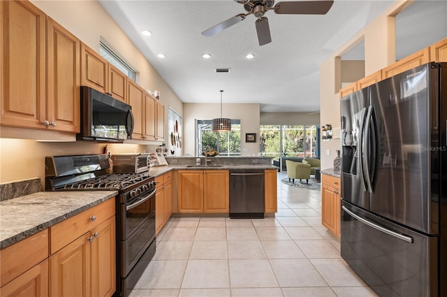 kitchen with light tile patterned flooring, a sink, dark stone countertops, a peninsula, and black appliances