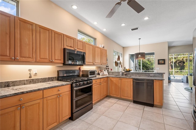 kitchen with light tile patterned floors, stainless steel appliances, a sink, visible vents, and dark stone countertops