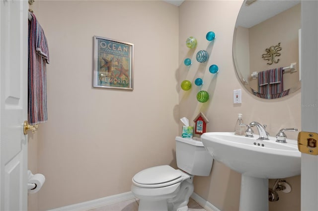 bathroom with a sink, toilet, and baseboards