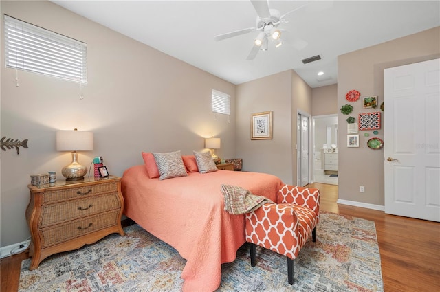 bedroom with baseboards, visible vents, multiple windows, and wood finished floors