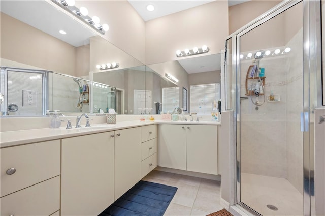 bathroom featuring double vanity, a stall shower, a sink, and tile patterned floors