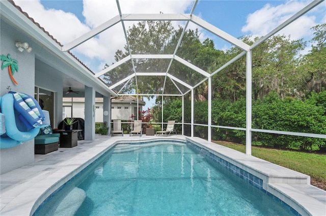 pool with a patio area, glass enclosure, and a ceiling fan