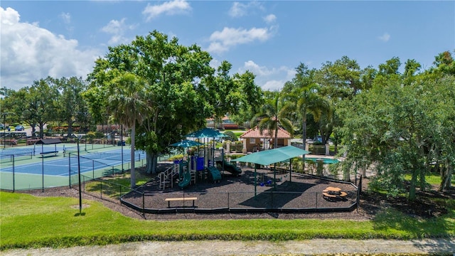 community jungle gym featuring a tennis court, a yard, and fence